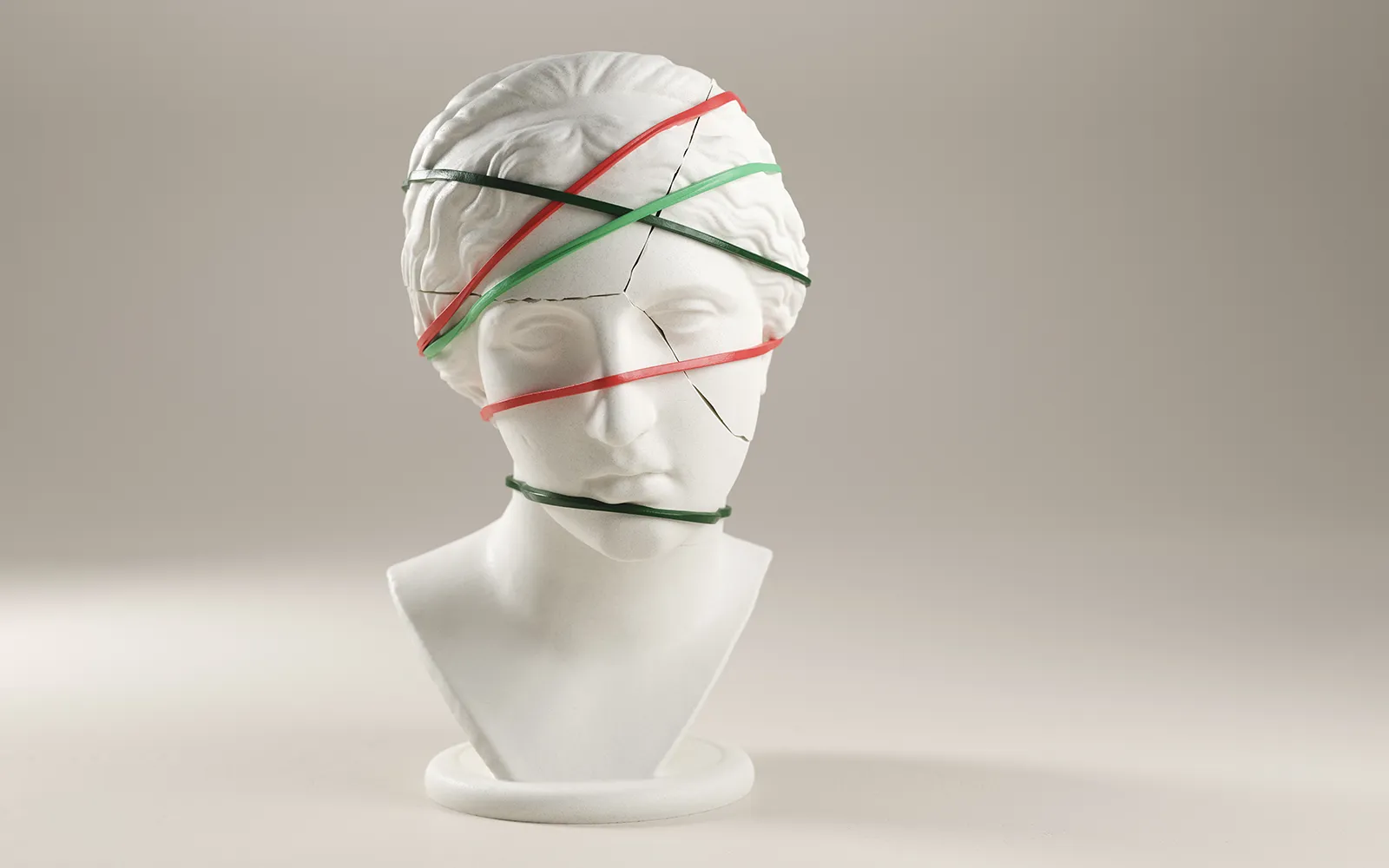 A porcelain bust with cracks with rubber bands holding it together.